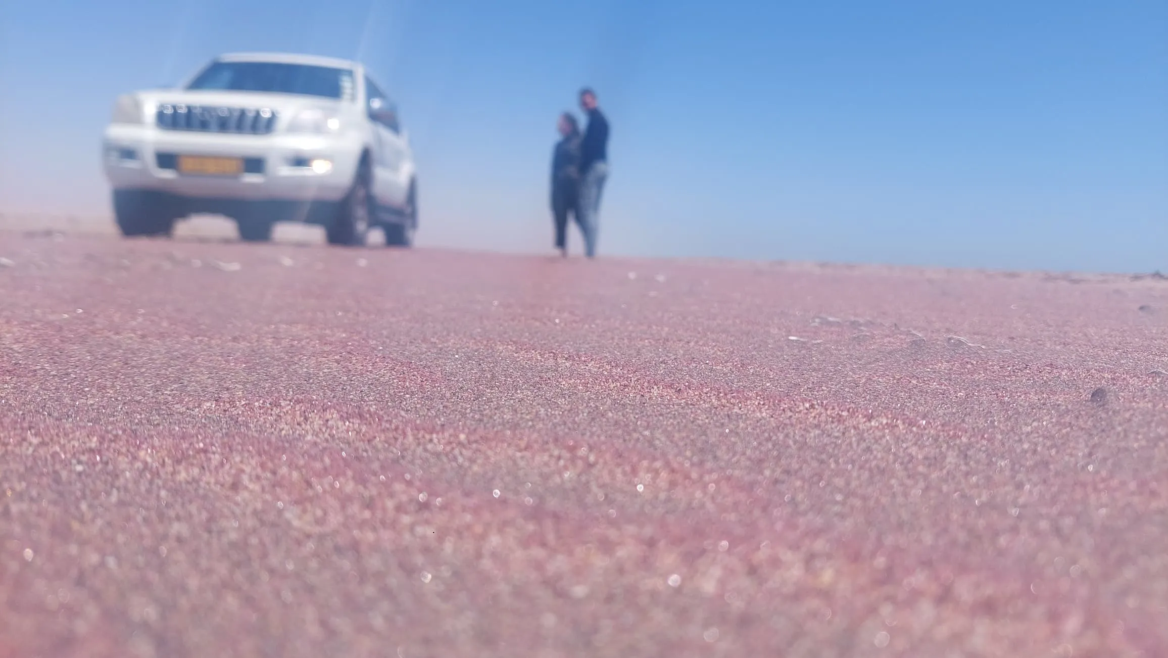 4x4 vehicle driving through massive red dunes at Sandwich Harbour, Namibia adventure tour